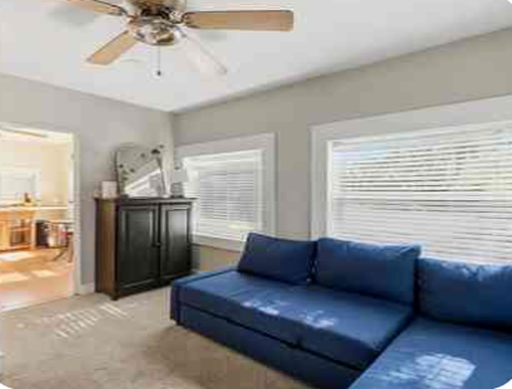 Upstairs residence living room with blue sectional and abundant windows